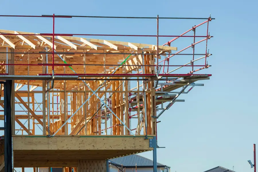 Holzständerwerk eines Neubaus hinter einem Baugerüst