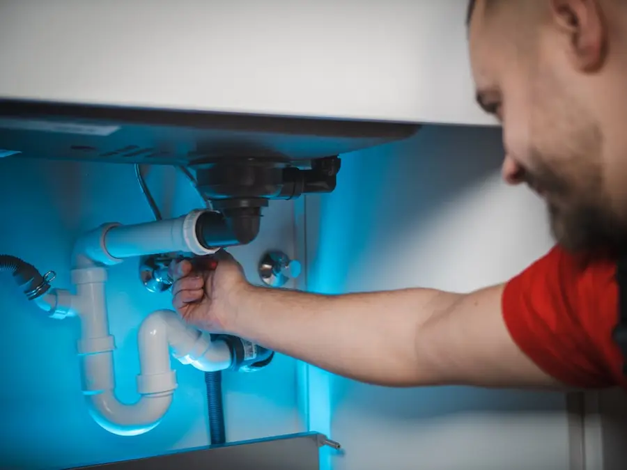Handwerker arbeitet am Siphon unter einem Waschbecken