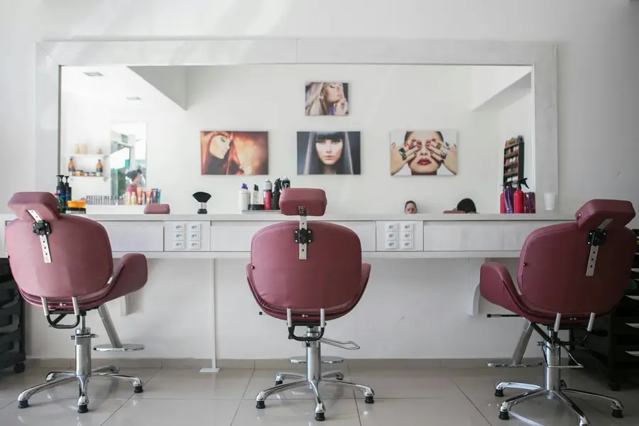 Drei Friseurstühle vor einer Spiegelwand