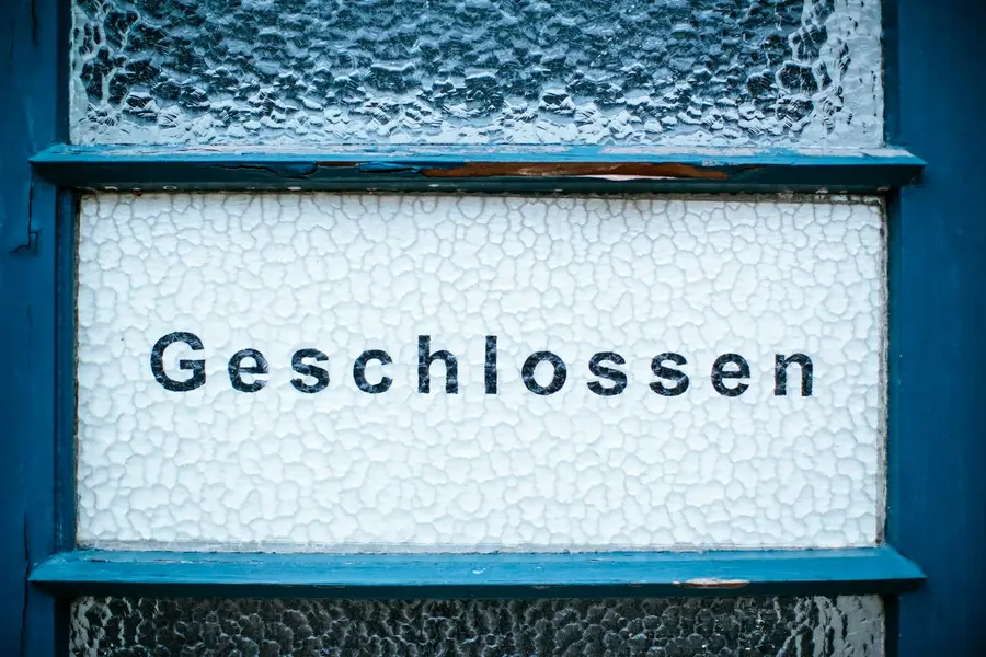 Schild mit der Aufschrift „Geschlossen" in einem blauen Fensterrahmen