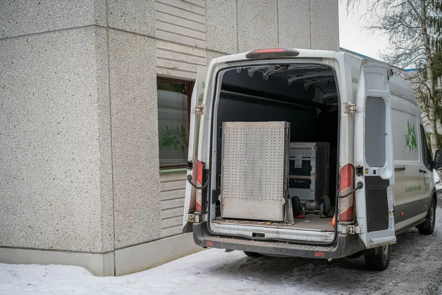 Weißer Transporter mit geöffneten Hecktüren, im Laderaum Werkzeug und eine Lochwand