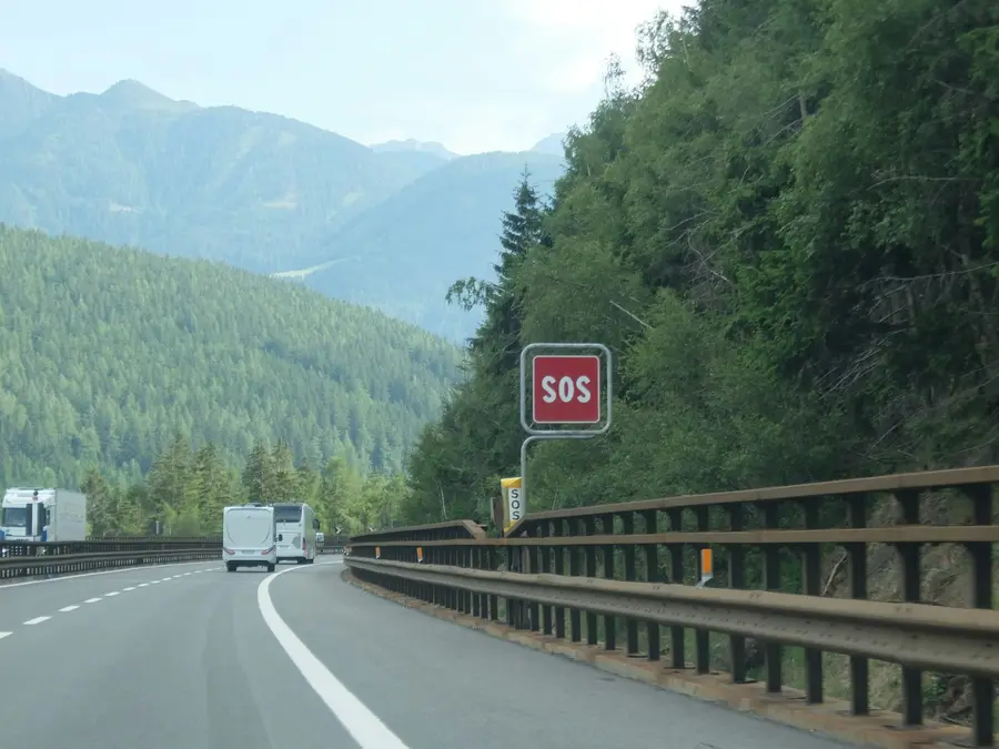 Autobahn im Gebirge, am Rand ein SOS-Schild der Notrufsäule