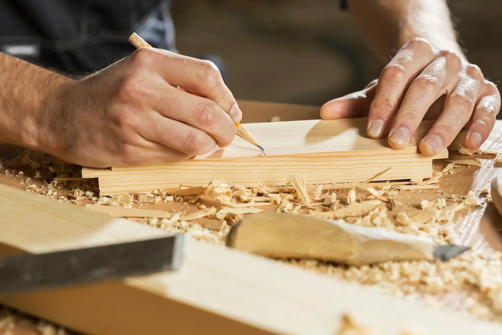 Hände zeichnen mit einem Bleistift Maße auf einem Werkstück aus Holz an