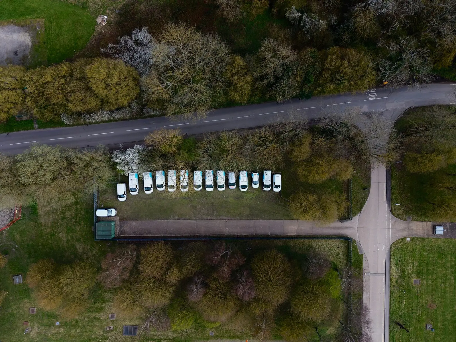 Eine Reihe weißer Kleinbusse auf einem Parkplatz aus der Vogelperspektive