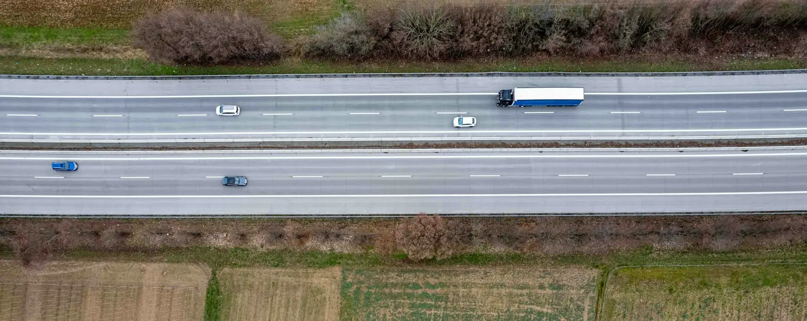 Ein Lastwagen fährt auf einer Autobahn durch eine grüne Landschaft