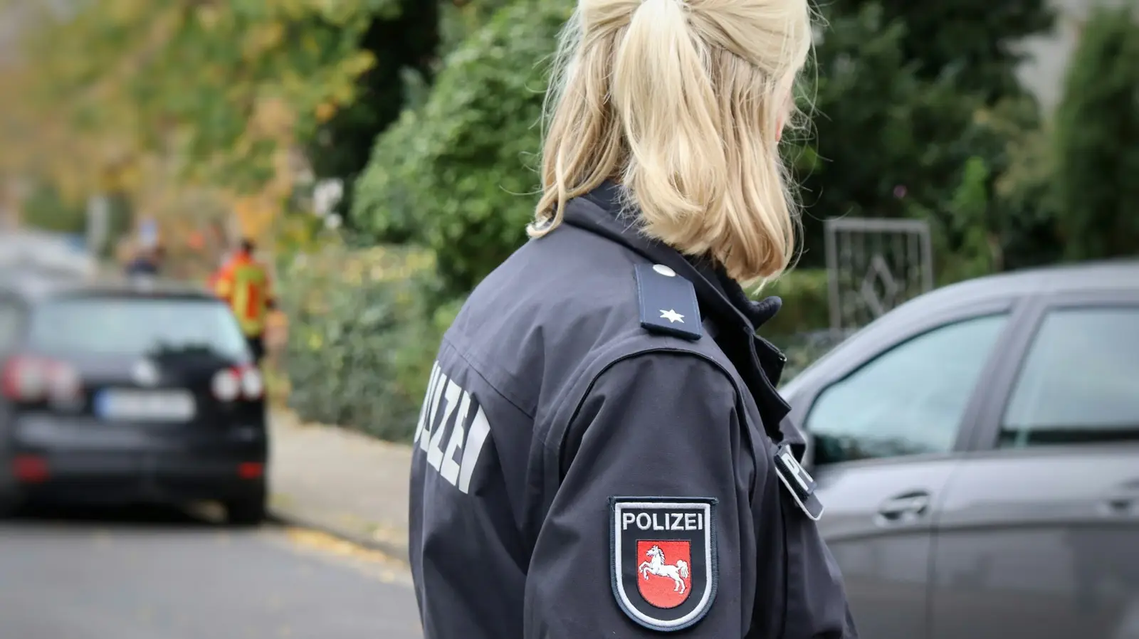 Polizistin in dunkelblauer Uniform von hinten auf einer Straße