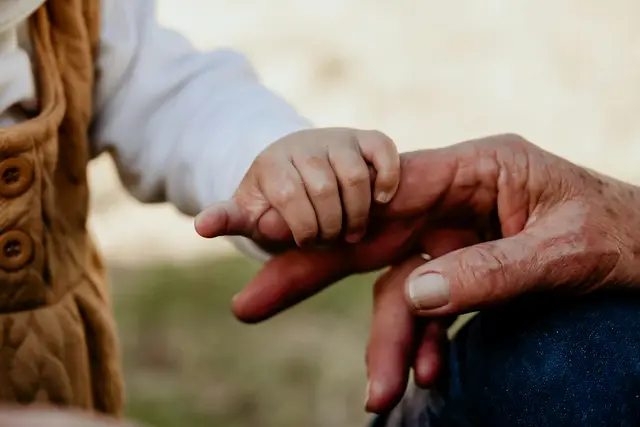Ein kleines Kind umfasst den Finger einer älteren Person