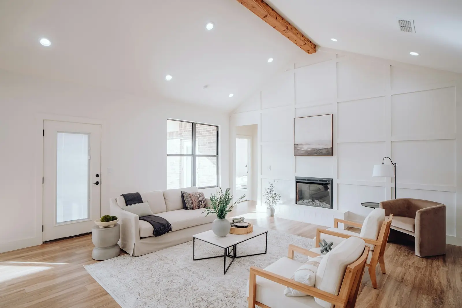 Helles Wohnzimmer mit Sofa, Sesseln und großen Fenstern