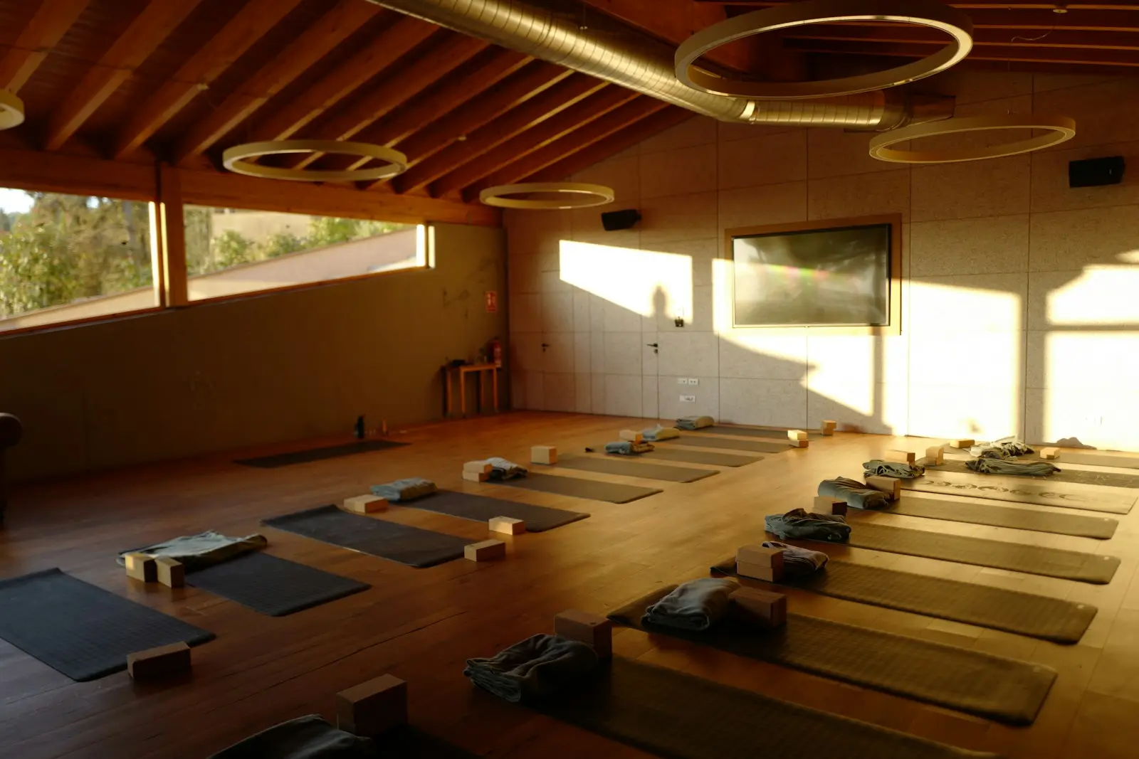 Yogamatten, Blöcke und Decken liegen in einem sonnigen Kursraum bereit