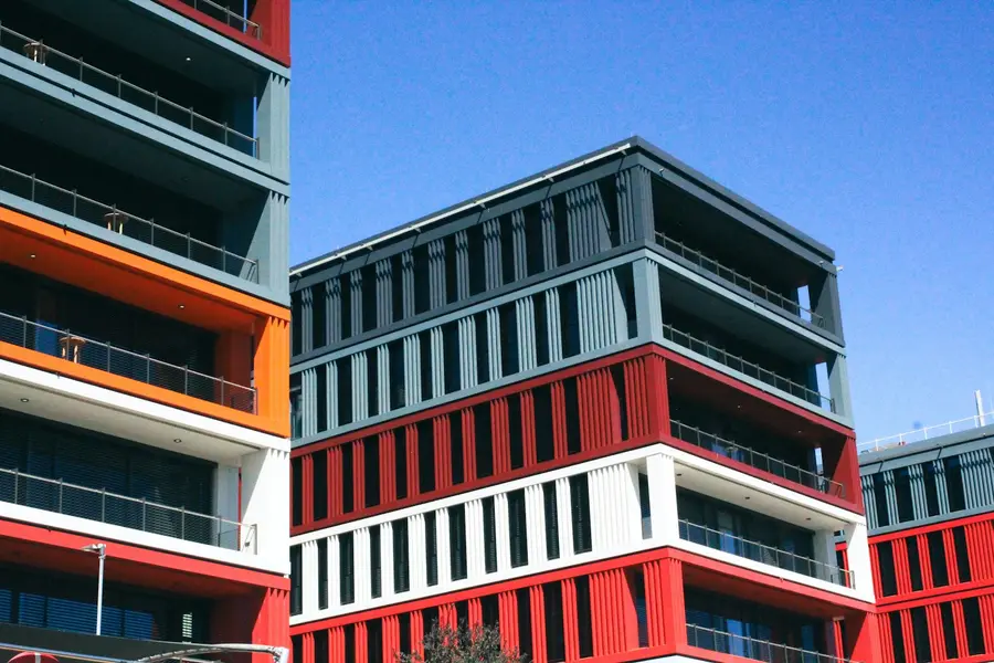 Neubau mit rot-weißer Fassade und umlaufenden Balkonen