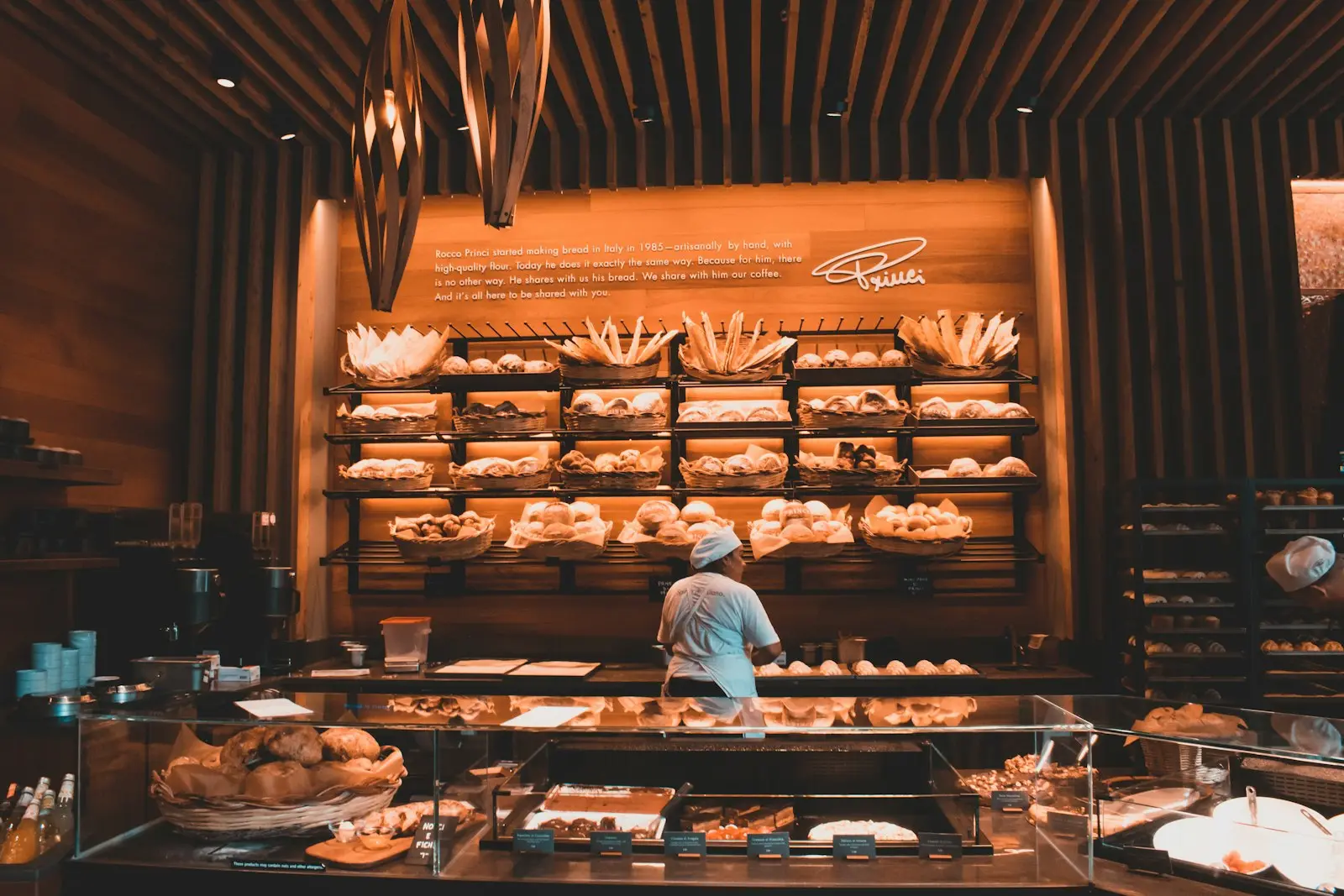 Bäckerei mit gefüllten Auslagen, im Hintergrund eine Mitarbeiterin