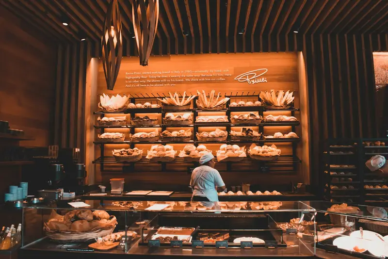 Bäckerei mit gefüllten Auslagen, im Hintergrund eine Mitarbeiterin