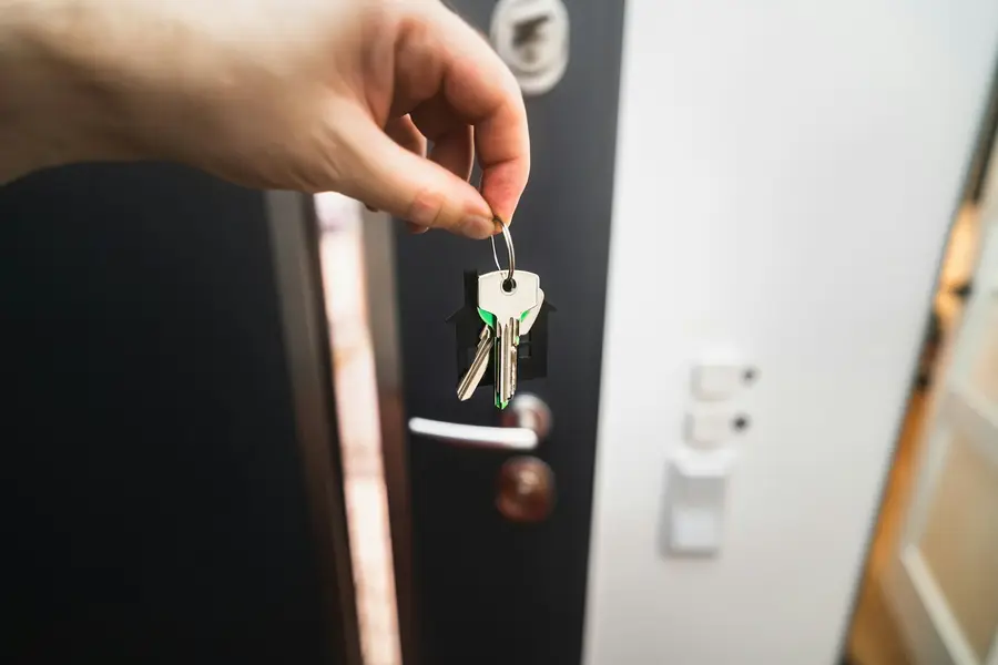 Hand steckt einen Schlüsselbund in das Schloss einer Wohnungstür