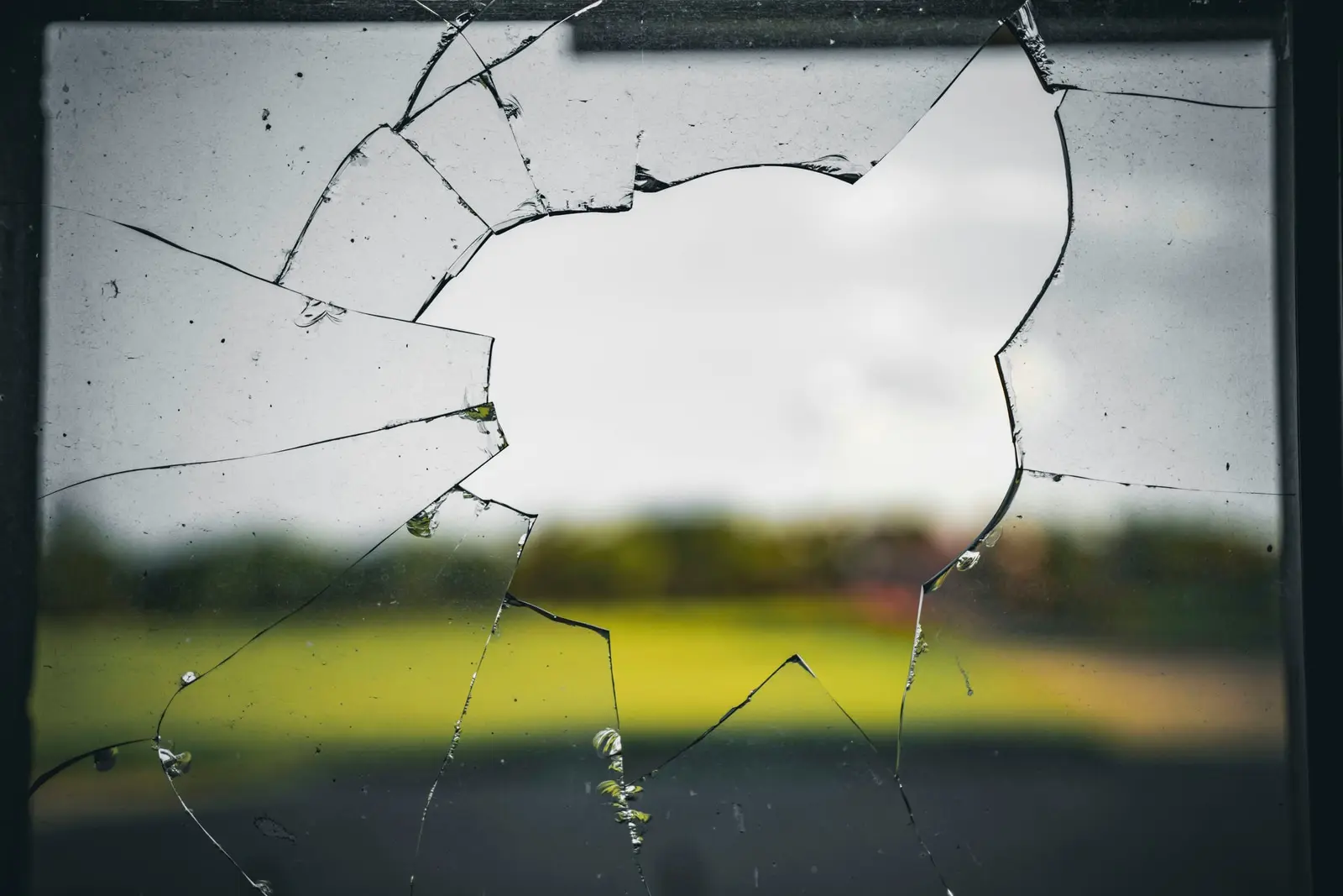 Gebrochene Fensterscheibe mit Rissen und fehlendem Glasstück