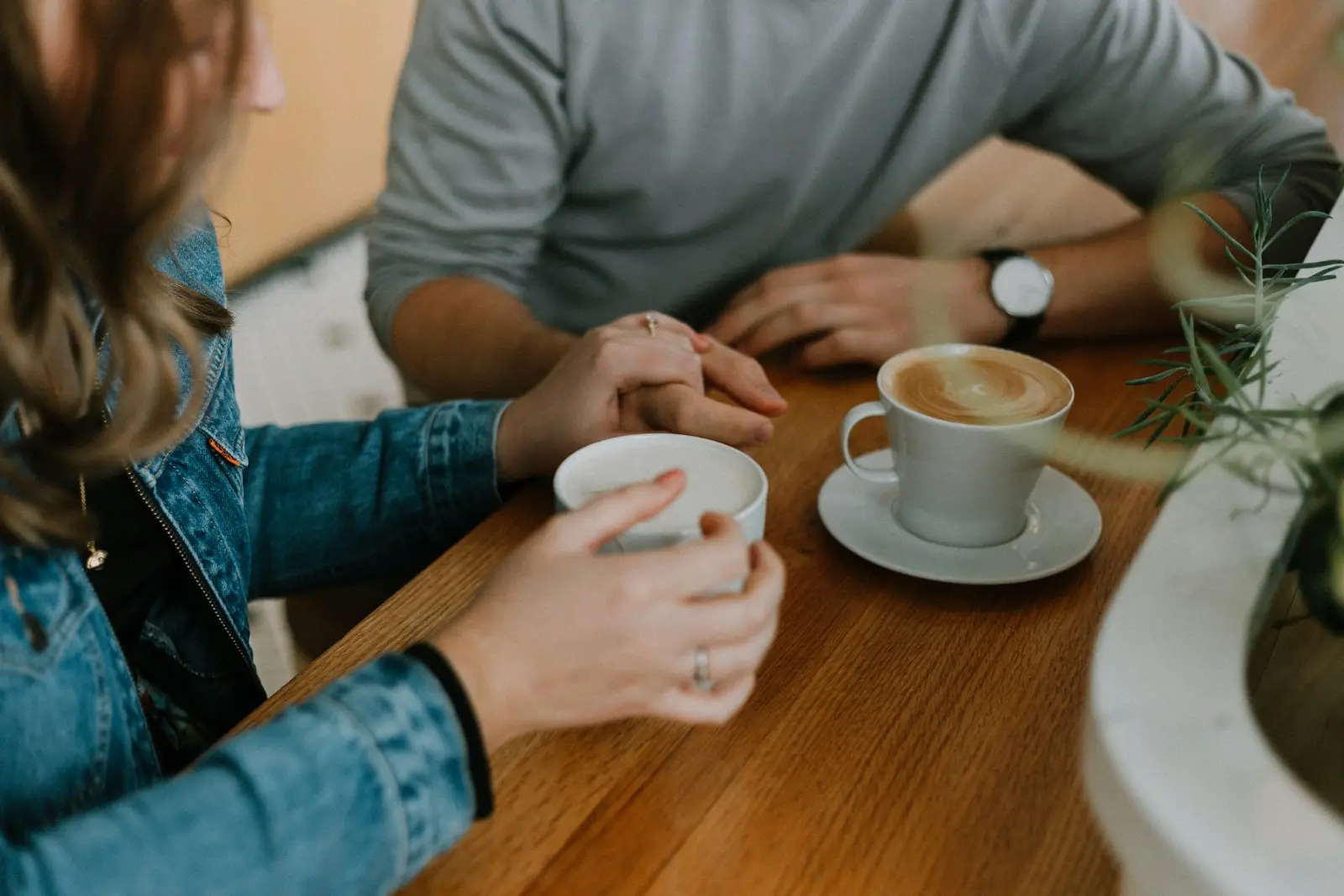 Zwei Menschen sitzen mit Kaffee an einem Tisch im Gespräch